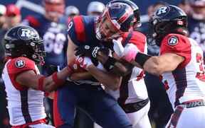 Jake Wieneke (9) des Alouettes de Montréal est plaqué par Patrick Levels du Rouge et Noir d'Ottawa, à gauche, et Adam Auclair, à droite, lors de la première mi-temps de la LCF à Montréal le lundi 10 octobre 2022.