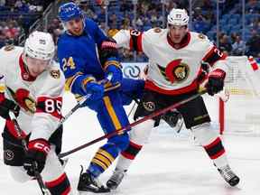 Travis Hamonic des Sénateurs d'Ottawa met en échec Dylan Cozens des Sabres de Buffalo alors que Jake Sanderson des Sénateurs d'Ottawa patine avec la rondelle au cours de la deuxième période au KeyBank Center.