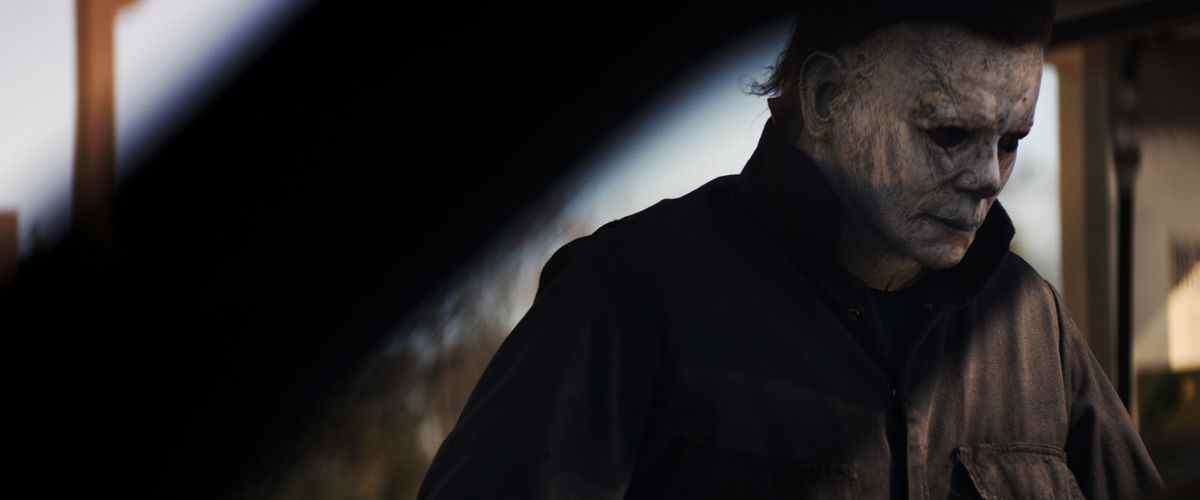 Le masqué Michael Myers dans le film Halloween de 2018, l'air assez hagard et regardant vers la droite.