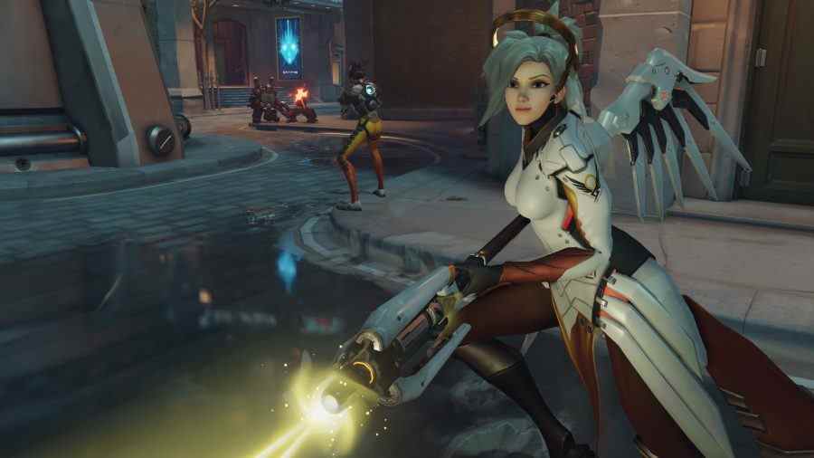 Rôles d'Overwatch 2 : le personnage de soutien Mercy tient son bâton bas, un faisceau jaune pulsant depuis la fin