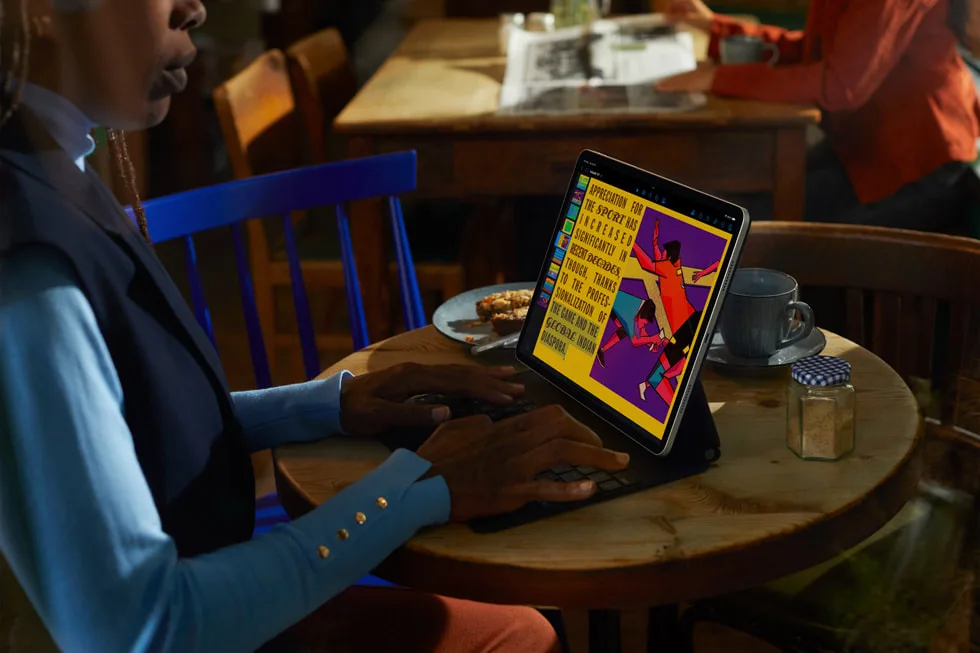 Une personne utilise un iPad Pro assis à une table.