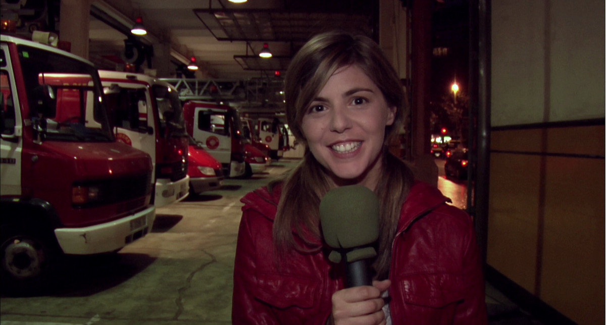 Une jeune femme portant une veste rouge parle dans un microphone sur une émission télévisée d'une caserne de pompiers à Rec.