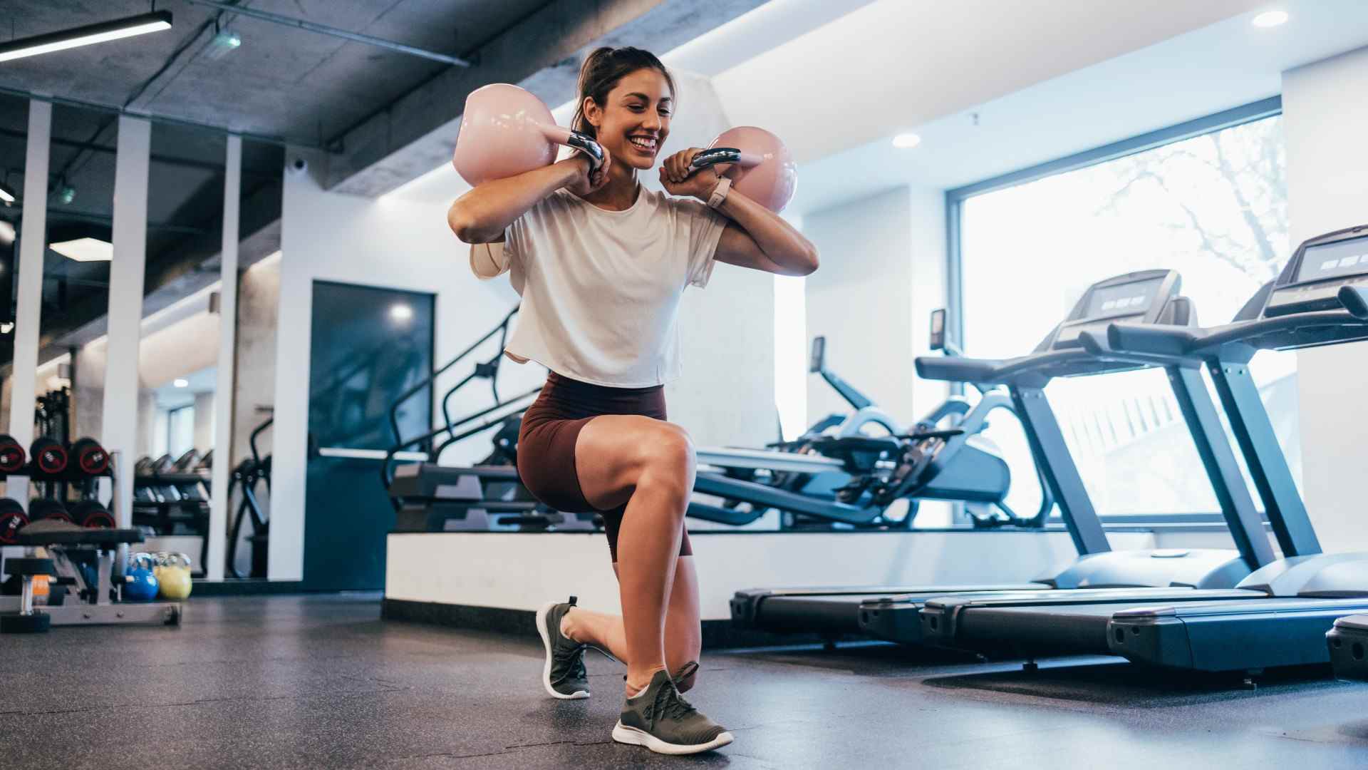 Personne exécutant une fente inversée kettlebell avec deux kettlebells en rack