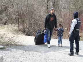 Des demandeurs d'asile entrent au Canada depuis la frontière américaine près d'un point de contrôle sur le chemin Roxham près de Hemmingford, Québec, Canada, le 24 avril 2022.