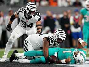 Le plaqueur défensif des Bengals de Cincinnati Josh Tupou (68) saccage le quart-arrière des Dolphins de Miami Tua Tagovailoa (1) au stade Paycor de Cincinnati.