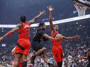 La recrue des Raptors Christian Koloko (à droite) monte avec OG Anunoby pour se défendre contre Darius Garland des Cavaliers lors du match d'ouverture de mercredi à la Scotiabank Arena.  Le Koloko de 7 pieds 1 pouce a eu un impact instantané dans ses 14 minutes sur le sol.