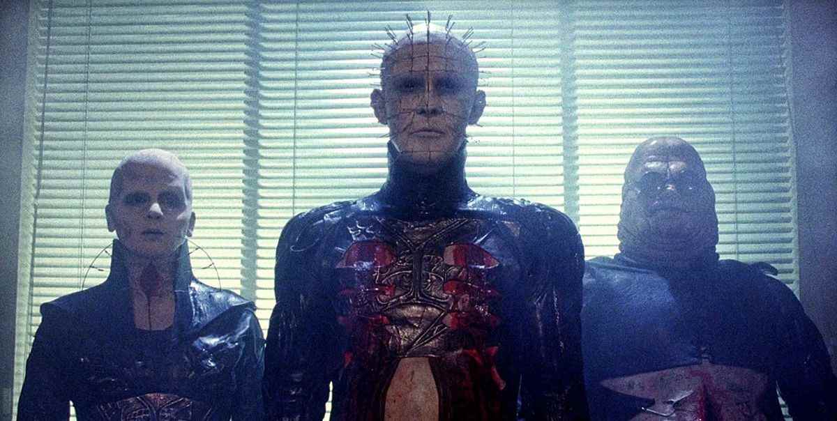 Pinhead flanqué de deux autres cénobites devant des stores à volets dans Hellraiser (1987)