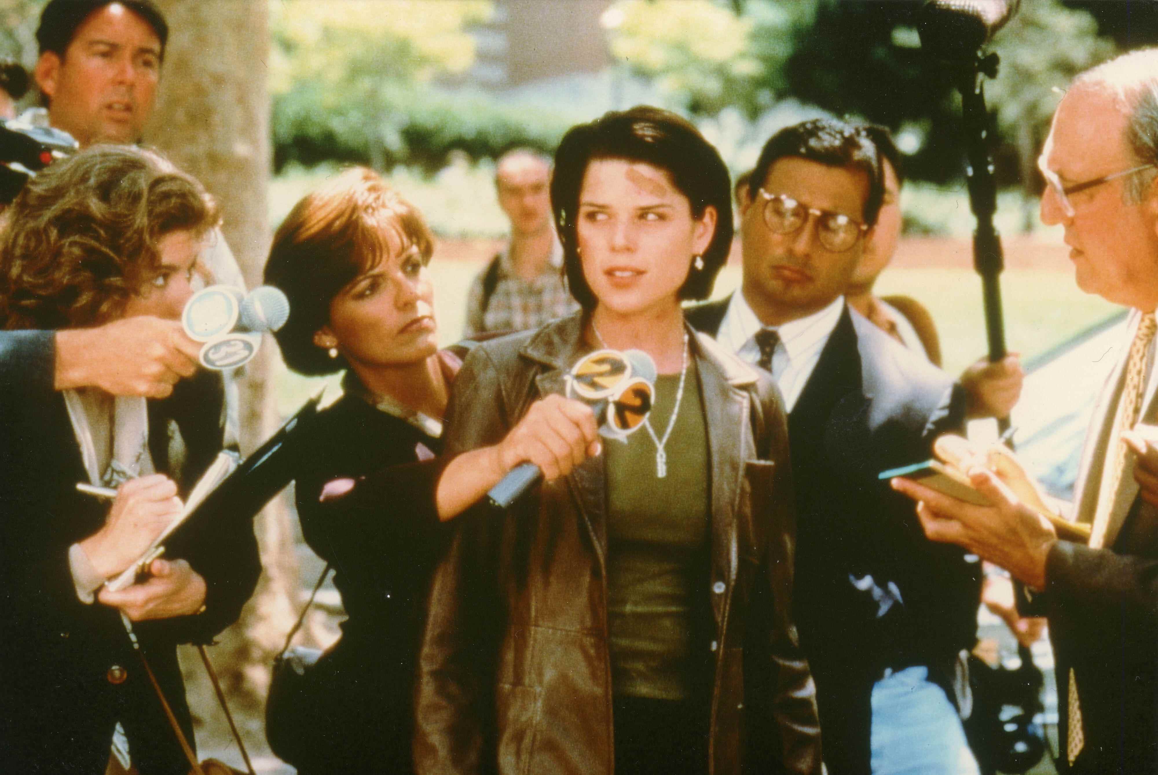 Neve Campbell (comme Sidney Prescott), s'adressant aux journalistes, dans le film Scream 2