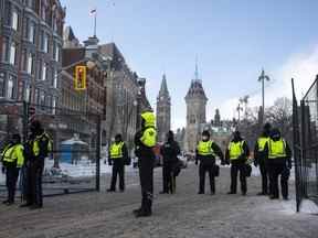 La Tour de la Paix est vue derrière la police à une porte le long de la rue Queen alors qu'ils restreignent l'accès aux rues autour de la Colline du Parlement à Ottawa, le samedi 19 février 2022. L'enquête sur l'utilisation par le gouvernement fédéral de la Loi sur les mesures d'urgence au cours de la "Convoi de la liberté" la manifestation à Ottawa se poursuit aujourd'hui.