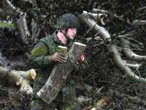 Cpl.  Brandon McRae des Cape Breton Highlanders enlève les broussailles sous la direction des responsables de Nova Scotia Power à Glace Bay, N.-É., le 26 septembre 2022.