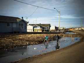 Des enfants autochtones jouent dans des fossés remplis d'eau à Attawapiskat, en Ontario.