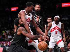 La garde des Brooklyn Nets Kyrie Irving (11) tente de voler le ballon à l'attaquant des Raptors de Toronto Christian Koloko (35) au Barclays Center.