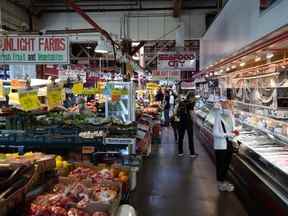 Les gens achètent des produits et des fruits de mer au marché de Granville Island à Vancouver, le mercredi 20 juillet 2022.