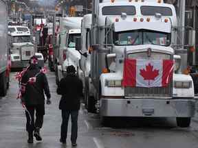 Les manifestants marchent entre les camions garés le long de la rue Wellington au centre-ville d'Ottawa alors que le 