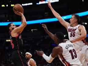 Le garde des Raptors de Toronto Fred VanVleet (23 ans) tire le ballon au-dessus du centre Bam Adebayo (13 ans) et du garde des Miami Heat Duncan Robinson (55 ans) au cours de la première mi-temps à la FTX Arena lundi soir.