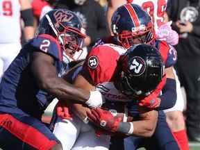 Micah Awe, à gauche, des Alouettes de Montréal, et Wesley Sutton font tomber Jackson Bennett du Rouge et Noir d'Ottawa en deuxième demie à Montréal le 10 octobre 2022.