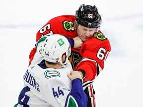 Le défenseur des Canucks de Vancouver Kyle Burroughs (44) se bat avec le défenseur des Blackhawks de Chicago Riley Stillman (61) au cours de la première période au United Center.