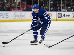 Le centre des Maple Leafs de Toronto Denis Malgin fait avancer la rondelle alors qu'il est défendu par les défenseurs des Red Wings de Detroit Wyatt Newpower lors de la deuxième période d'action pré-saison de la LNH, à Toronto, le samedi 8 octobre 2022.