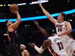 Le garde des Raptors Fred VanVleet (23 ans) tire le ballon sur le centre Bam Adebayo (13 ans) et le garde des Miami Heat Duncan Robinson (55 ans) au cours de la première mi-temps à Miami lundi soir.