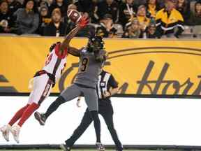 Le demi défensif des Redblacks Brandin Dandridge éloigne le ballon du receveur des Tiger-Cats Steven Dunbar Jr. (8) au cours de la première mi-temps.