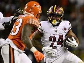 Antonio Gibson, à droite, des Commanders porte le ballon contre les Bears lors du troisième quart-temps au Soldier Field de Chicago, le jeudi 13 octobre 2022.