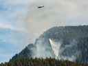 Un hélicoptère déverse de l'eau sur un feu de forêt à West Vancouver le vendredi 14 octobre 2022.