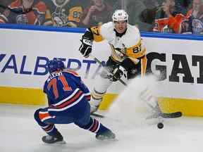 Le capitaine des Penguins de Pittsburgh Sidney Crosby (87) est contrôlé par les Oilers d'Edmonton Ryan McLeod (71) lors de la première période d'action de jeu de la Ligue nationale de hockey à Edmonton le lundi 24 octobre 2022. Les Oilers ont vaincu les Penguins 6-3.