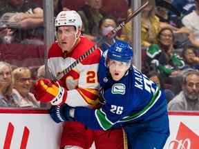 Le défenseur des Flames de Calgary Michael Stone affronte le défenseur des Canucks de Vancouver Wyatt Kalynuk lors d'un match de pré-saison au Rogers Arena de Vancouver le 25 septembre 2022.