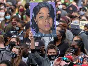 Un manifestant brandit un portrait de Breonna Taylor lors d'un rassemblement en souvenir à l'occasion du premier anniversaire de sa mort à Louisville, Kentucky.