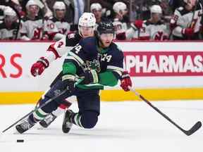 Ethan Bear (74 ans) des Canucks de Vancouver patine avec la rondelle devant Nathan Bastian (14 ans) des Devils du New Jersey lors de la deuxième période d'un match de hockey de la LNH à Vancouver, en Colombie-Britannique, le mardi 1er novembre 2022.