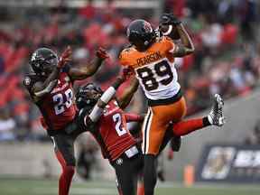 Le receveur large des Lions de la Colombie-Britannique Josh Pearson (89) attrape le ballon alors que le demi défensif des Redblacks d'Ottawa Randall Evans (2) et le secondeur Frankie Griffin (28) l'atteignent, lors de la première mi-temps de l'action de football de la LCF à Ottawa le jeudi 30 juin 2022. PRESSE CANADIENNE/Justin Tang