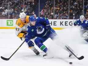 Tyler Myers (57 ans) des Canucks de Vancouver et Michael McCarron (47 ans) des Predators de Nashville se disputent la rondelle lors de la première période d'un match de hockey de la LNH à Vancouver, le samedi 5 novembre 2022.