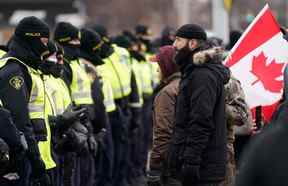 Des policiers se déploient pour déplacer des manifestants bloquant l'accès au pont Ambassador et exigeant la fin des mandats du gouvernement COVID-19, à Windsor, en Ontario, le samedi 12 février 2022.