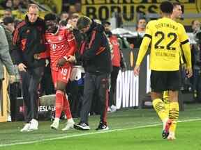 Le milieu de terrain canadien du Bayern Munich Alphonso Davies (deuxième à gauche) réagit blessé sur la touche lors du match de football de première division allemande de la Bundesliga entre le BVB Borussia Dortmund et le FC Bayern Munich à Dortmund, dans l'ouest de l'Allemagne, le 8 octobre 2022.