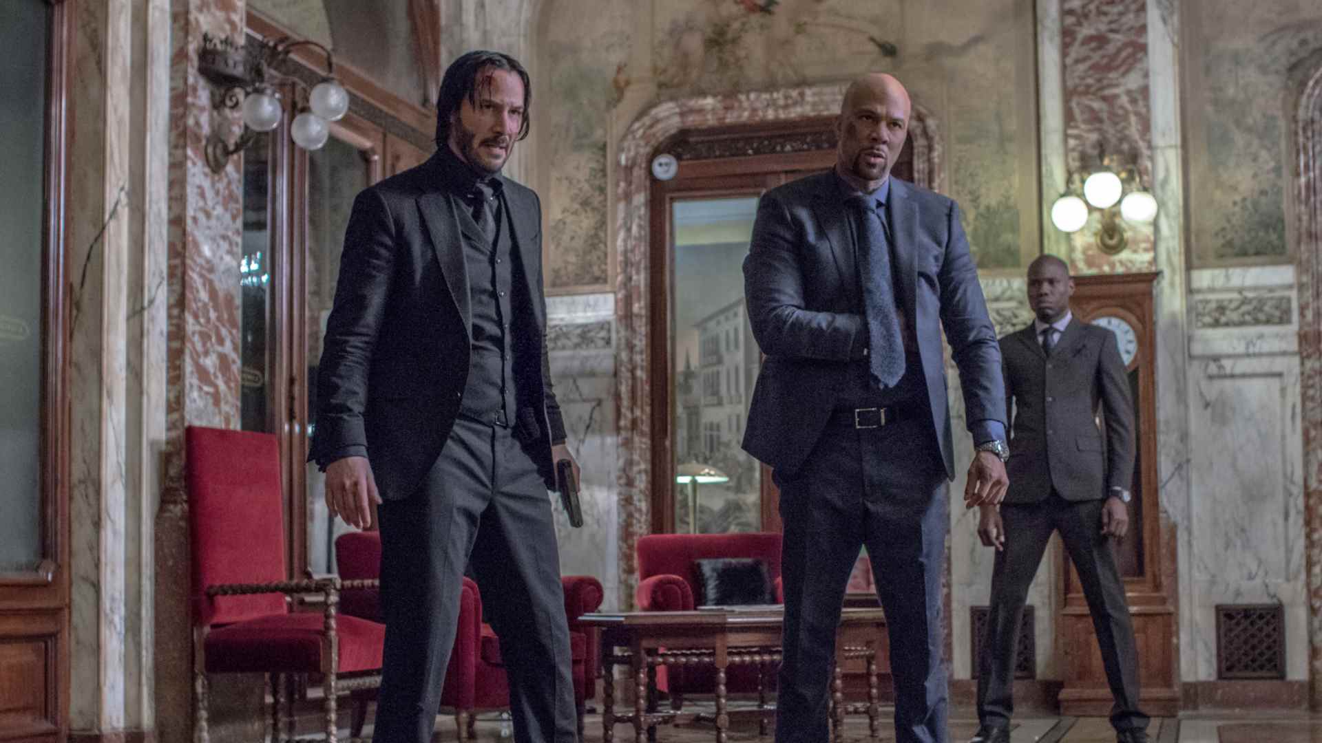 John Wick se tient aux côtés d'un autre assassin, le couple ayant l'air en colère, dans l'un des films de John Wick