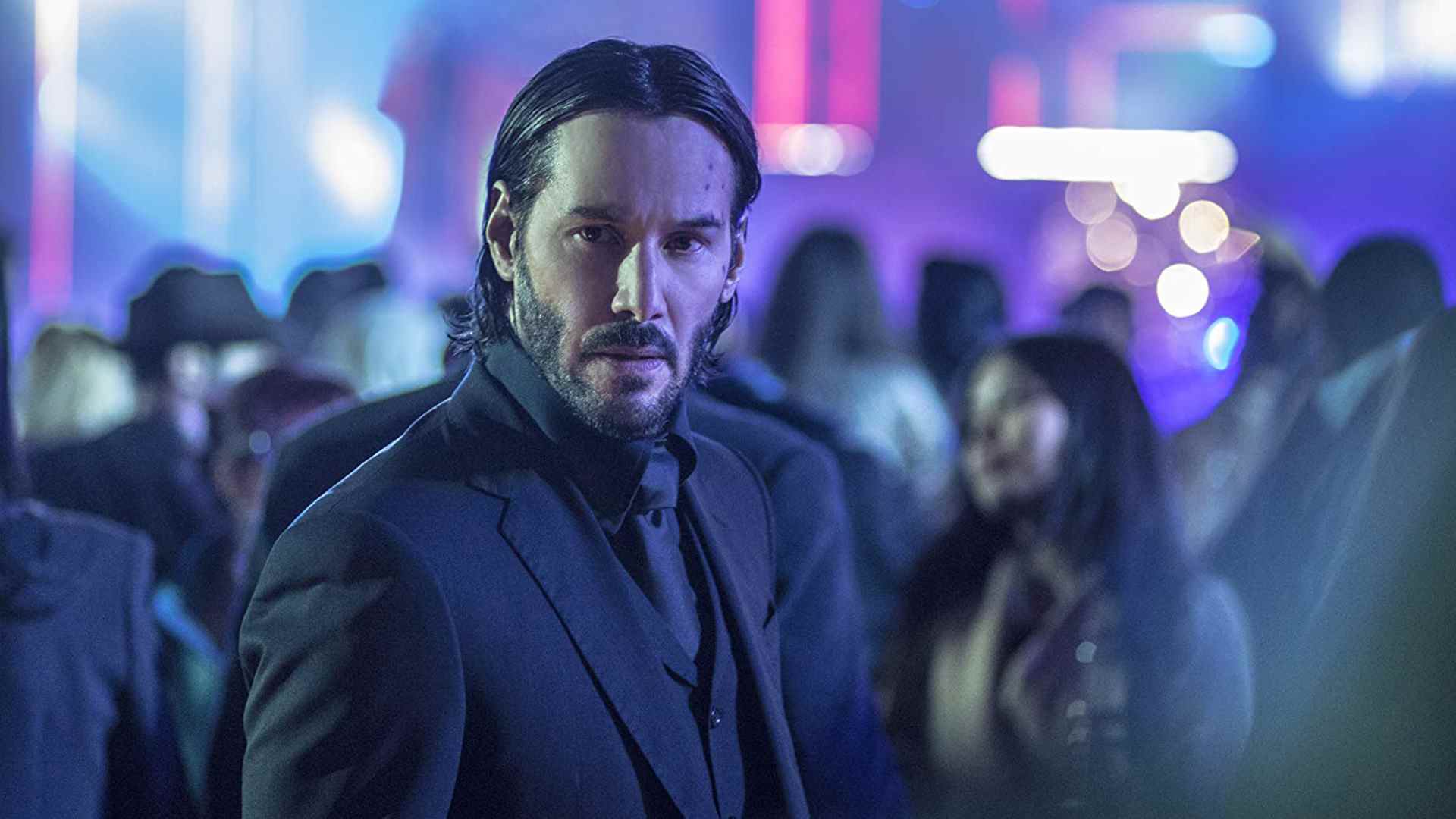 Un John Wick bien adapté cherche quelqu'un dans un décor de néon dans l'un de ses films