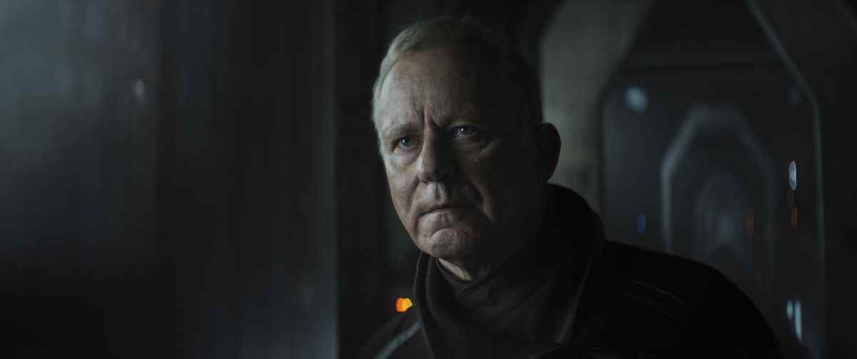 Luthen Rael (Stellan Skarsgard) avec un regard sérieux et un manteau noir en Andor.