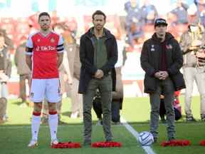 Les propriétaires de Wrexham, Ryan Reynolds et Rob McElhenney, se tiennent avec des couronnes dans le cadre des commémorations du souvenir avant le match Wrexham contre Torquay United.