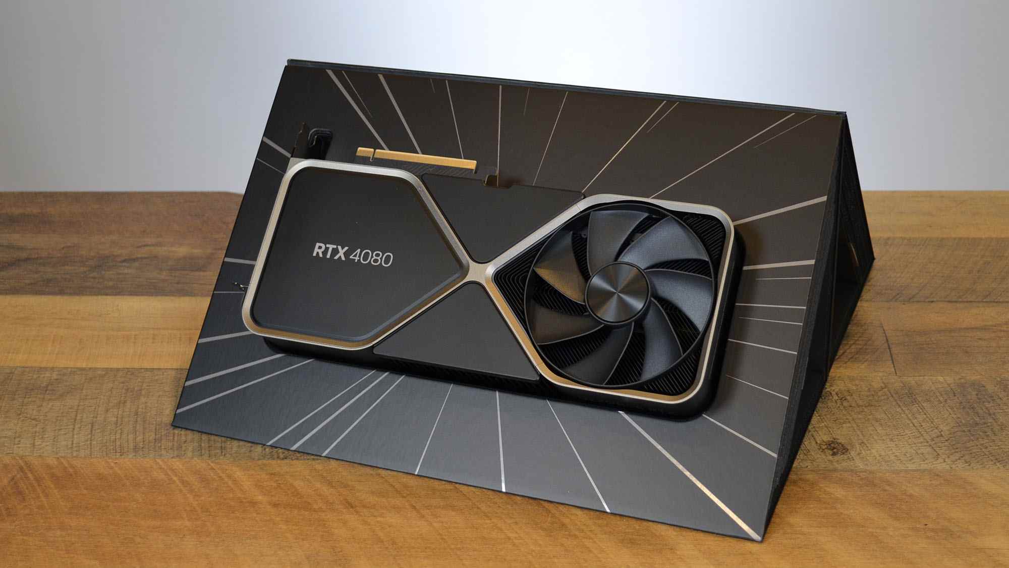 Une Nvidia GeForce RTX 4080 sur un bureau en bois devant un panneau blanc