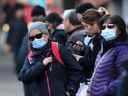 Des navetteurs masqués attendent leur bus au centre-ville de Vancouver lundi.