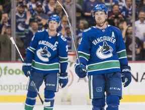 Henrik Sedin, à gauche, et Daniel Sedin, à droite, saluent les partisans des Canucks après avoir disputé leur dernier match à domicile de leur carrière dans la LNH, au Rogers Arena de Vancouver, le 5 avril 2018.