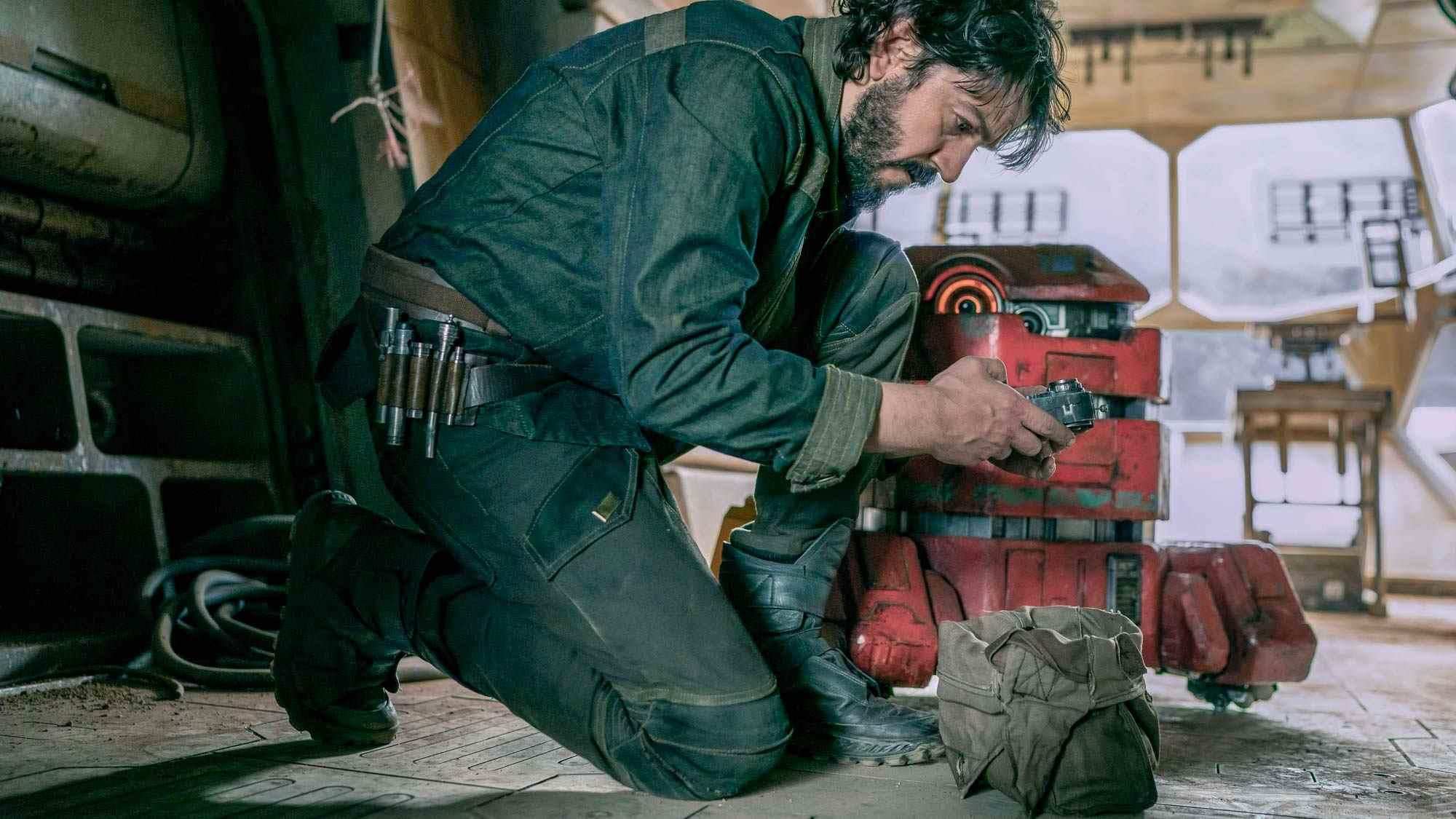 (De gauche à droite) Cassian Andor (Diego Luna) s'agenouille alors qu'il examine quelque chose tandis que B2EMO (Dave Chapman) est à sa gauche, à Andor