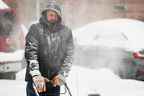 Un homme utilise une souffleuse à neige pendant une tempête de neige alors que des conditions hivernales extrêmes frappent Buffalo.