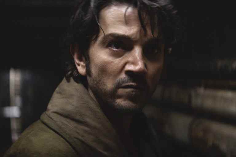 Shadowy close up on a man with dark hair, looking determined; still from "Andor."