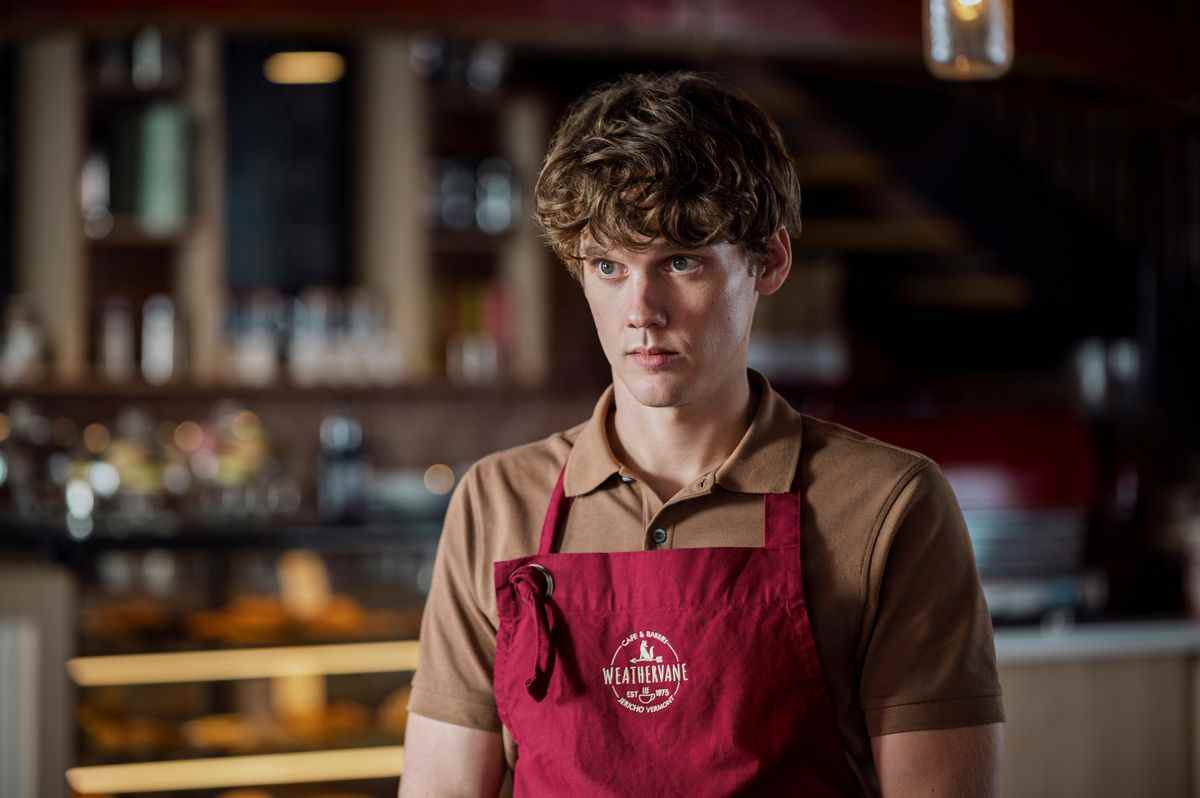 tyler, un grand garçon mince aux cheveux fauves bouclés, porte un tablier de barista le mercredi de netflix