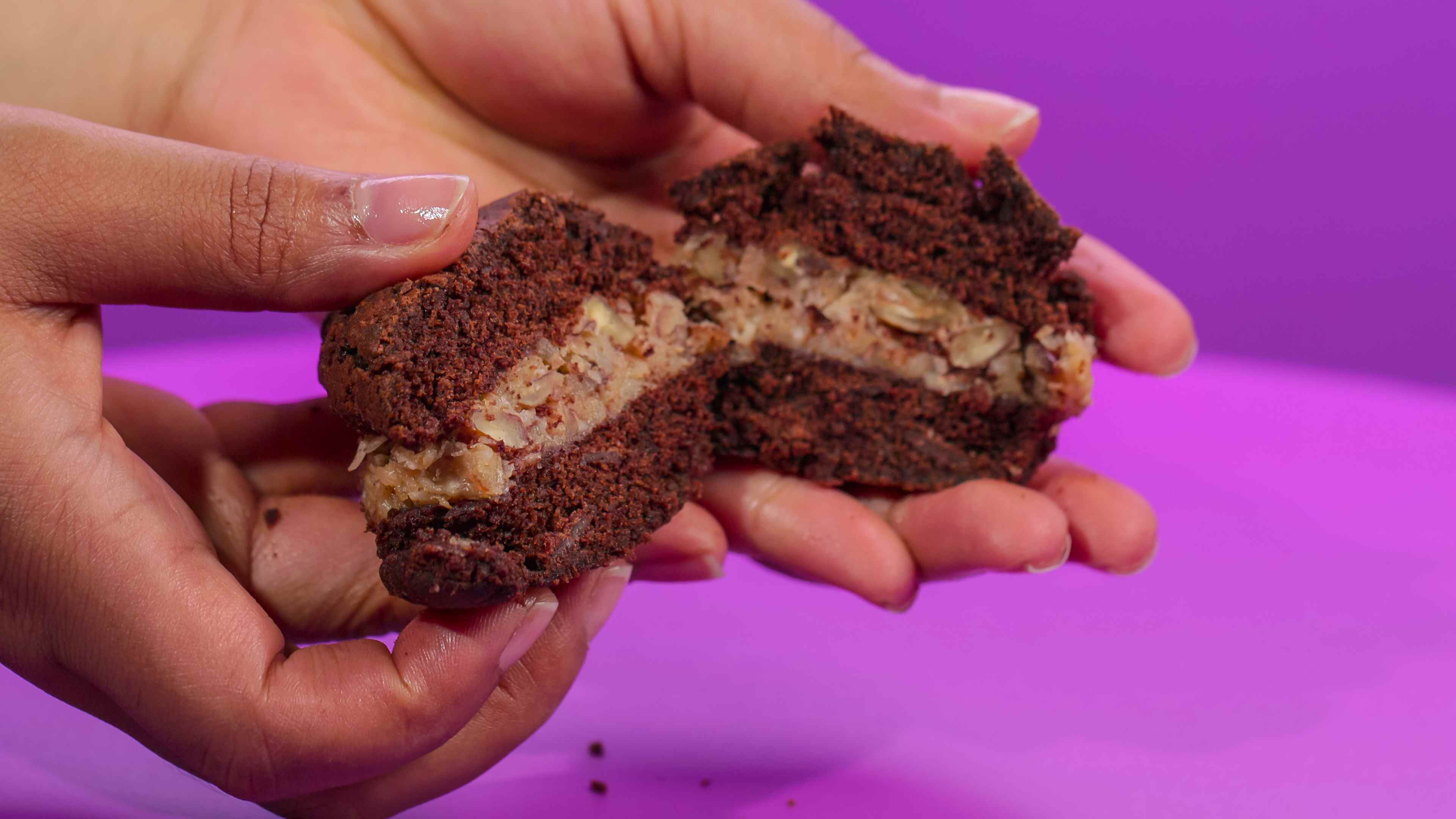 Une main tient un dessert rempli de crème au chocolat divisé en deux dans SNACK vs. CHEF