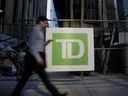 Un banlieusard passe devant la signalisation de la Banque Toronto-Dominion dans le quartier financier de Toronto.