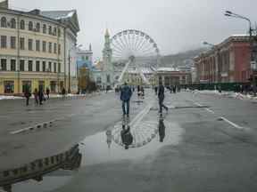 Des piétons passent devant une grande roue dans le quartier Padolsky de Kyiv au milieu de l'invasion russe de l'Ukraine.