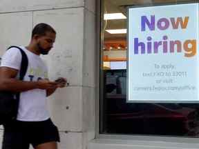 Un panneau « Now hiring » est accroché près de l'entrée d'un magasin Fedex à Miami Beach, en Floride.