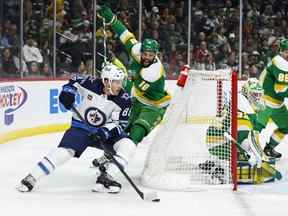 Le défenseur des Jets Nate Schmidt est poursuivi par l'ailier sauvage Jordan Greenway alors qu'il porte la rondelle derrière le filet du Minnesota mercredi soir au Xcel Energy Center de St Paul, Minn.